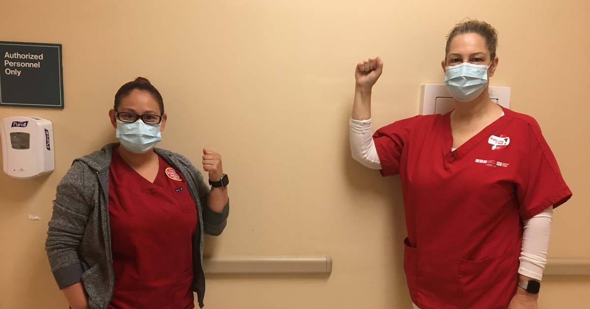 Two nurses inside hospital with fists raised