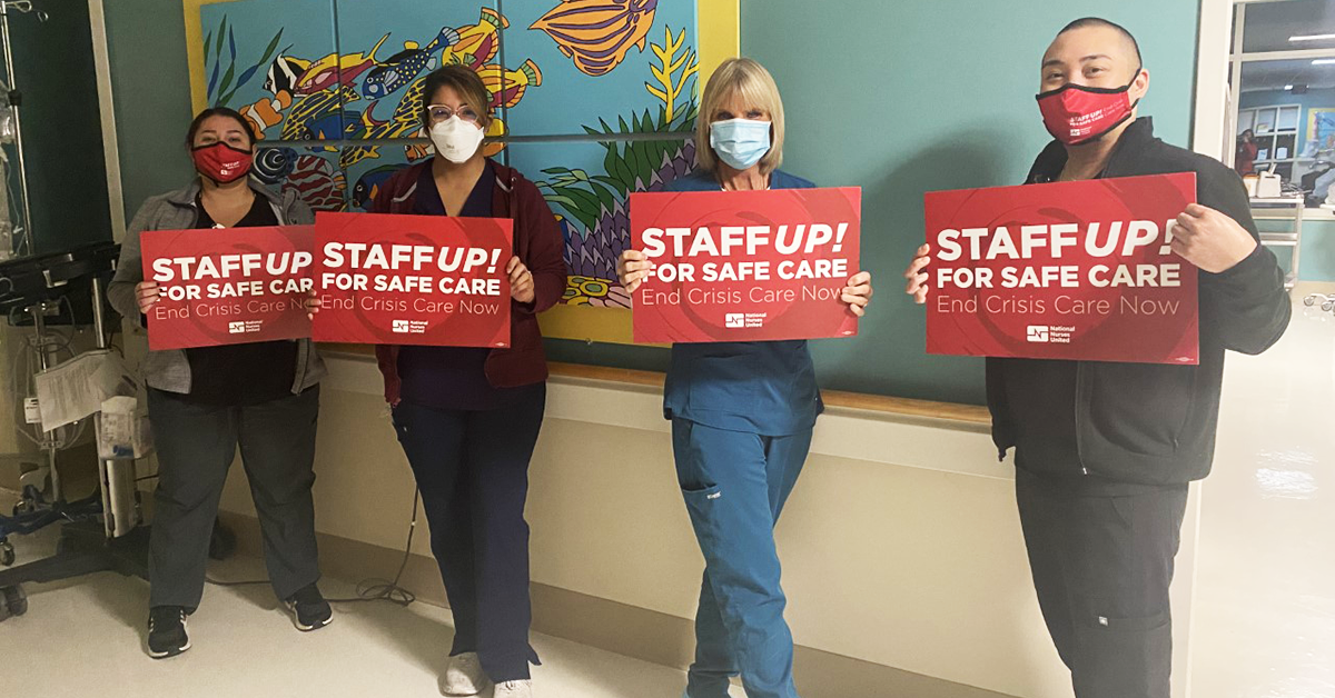 Four Monterey County RNs holding signs in hall "Staff up for safe care. End crisis care now."
