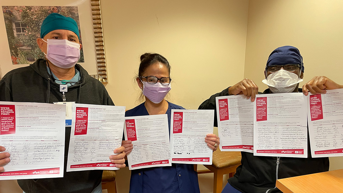 Three nurses inside hospital hold papers with signatures