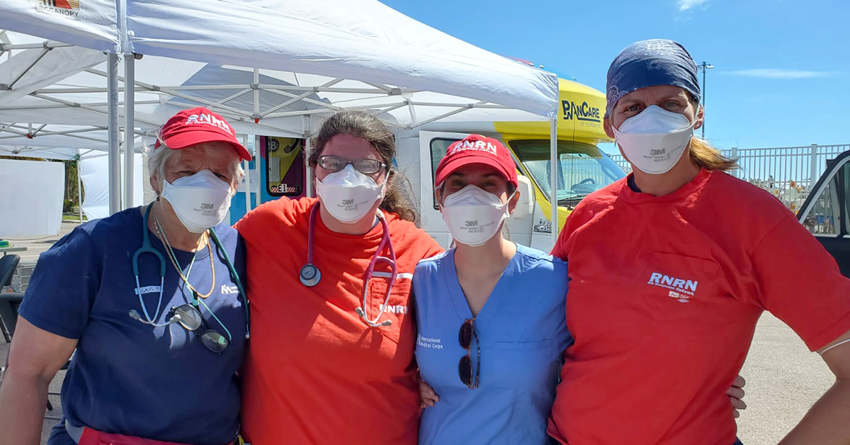 Four RNRN volunteers standing in front of tent