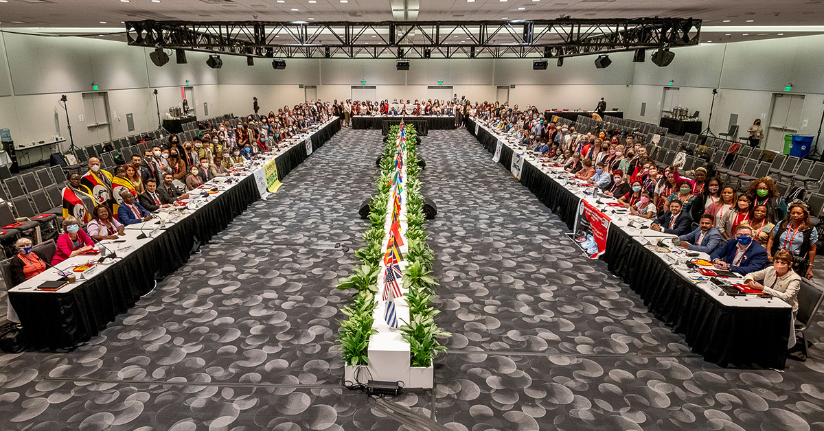 Large convention hall full of nurses seating at tables with their international flags