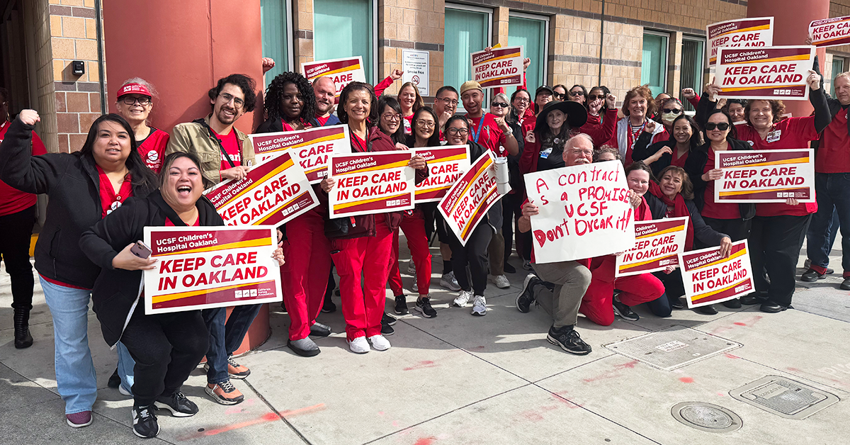Large group of nurses holding signs "Keep care in Oakland"