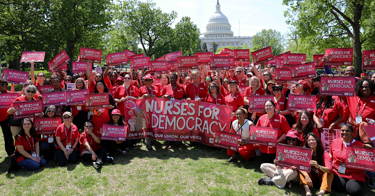 Group of nurses holding signs and banner "Nurses for Democracy"