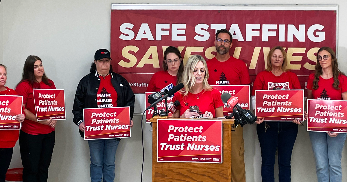 Nurses speaking at press event and holding signs "Protect Patients Trust Nurses" with banner in back "Safe staffing saves lives"
