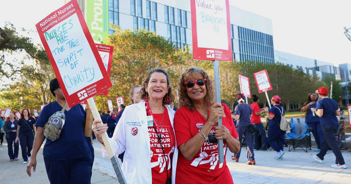 Nurses outside hospital holding signs "Nurses are the true spirit of charity"