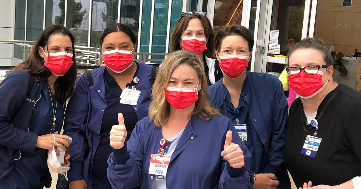 Group of nurses outside hospital with thumbs up