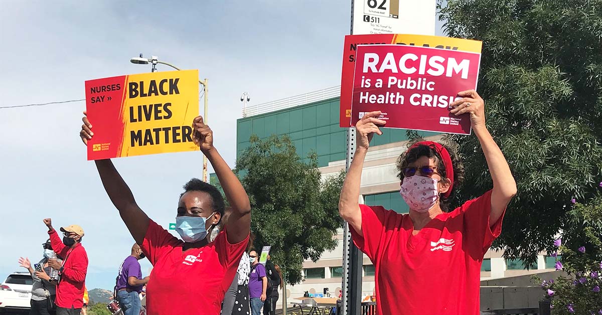 Nurses hold signs "Black Lives Matter" and "Racism is a public health crisis"