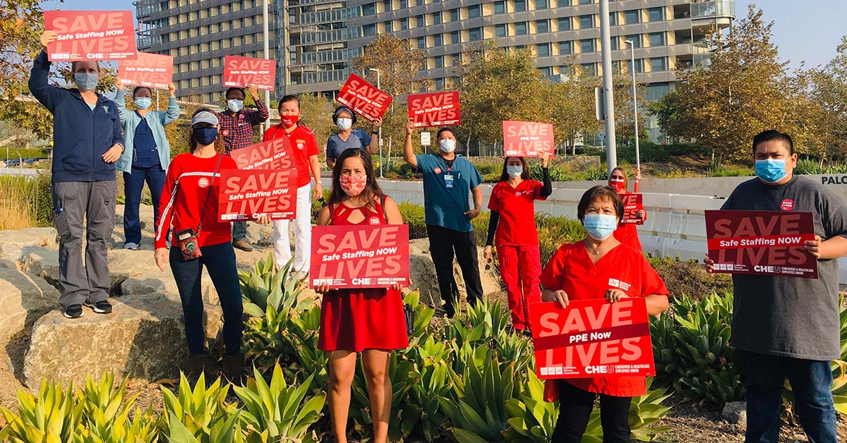 Group of healthcare workers outisde hopsital hold signs "Safe Staffing Now"