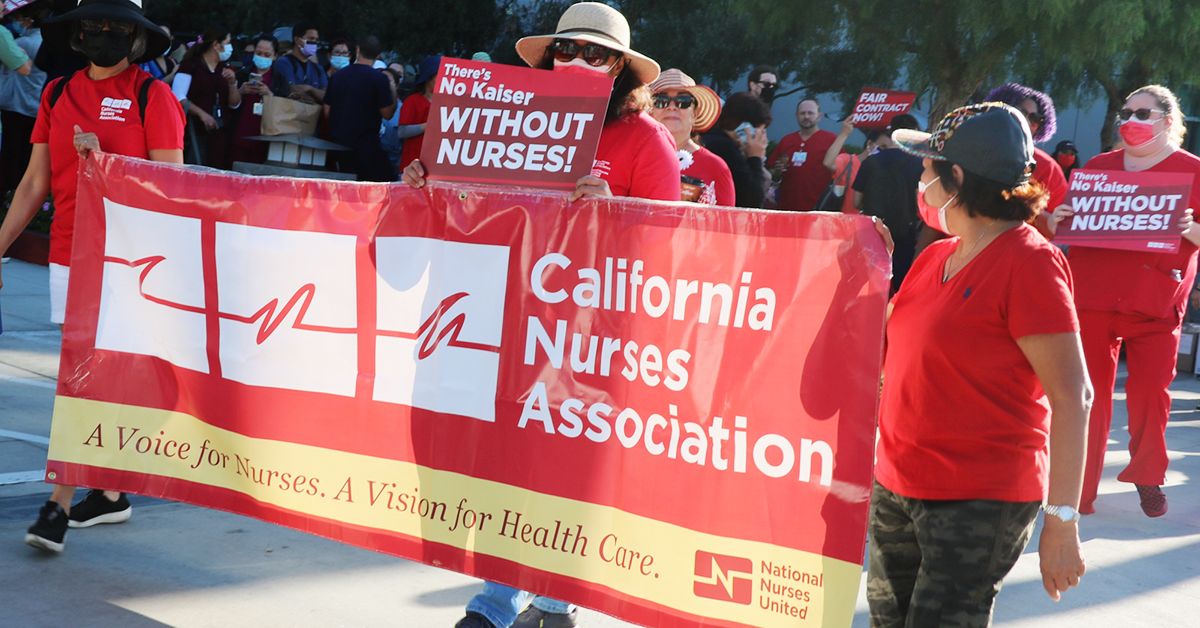 Nurses marching and holding CNA/NNU banner and signs at LAMC: "There's no Kaiser without nurses!"