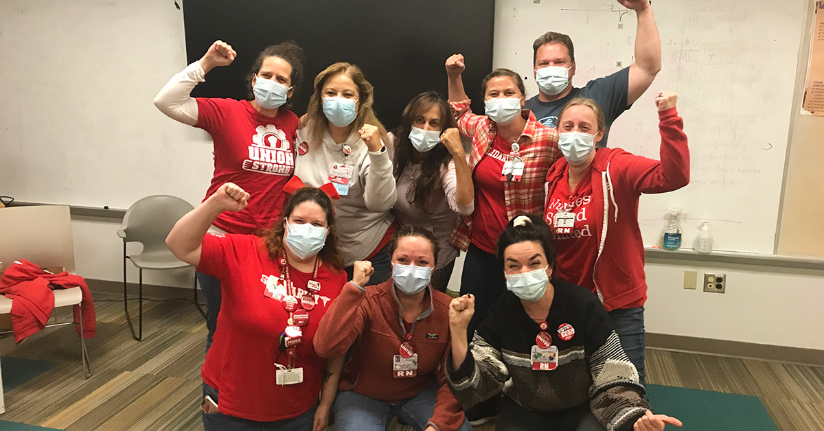 Group of nurses inside hospital with raised fists.