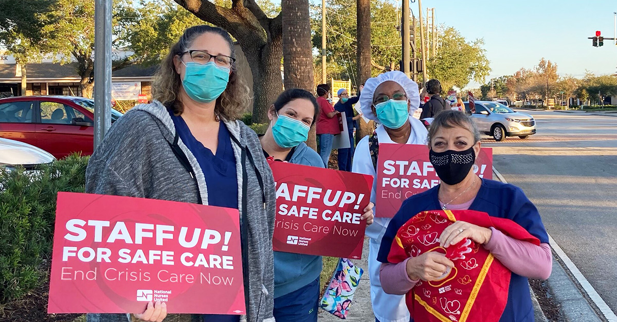 Group of four nurses outside hold signs "Staff up for safe care"