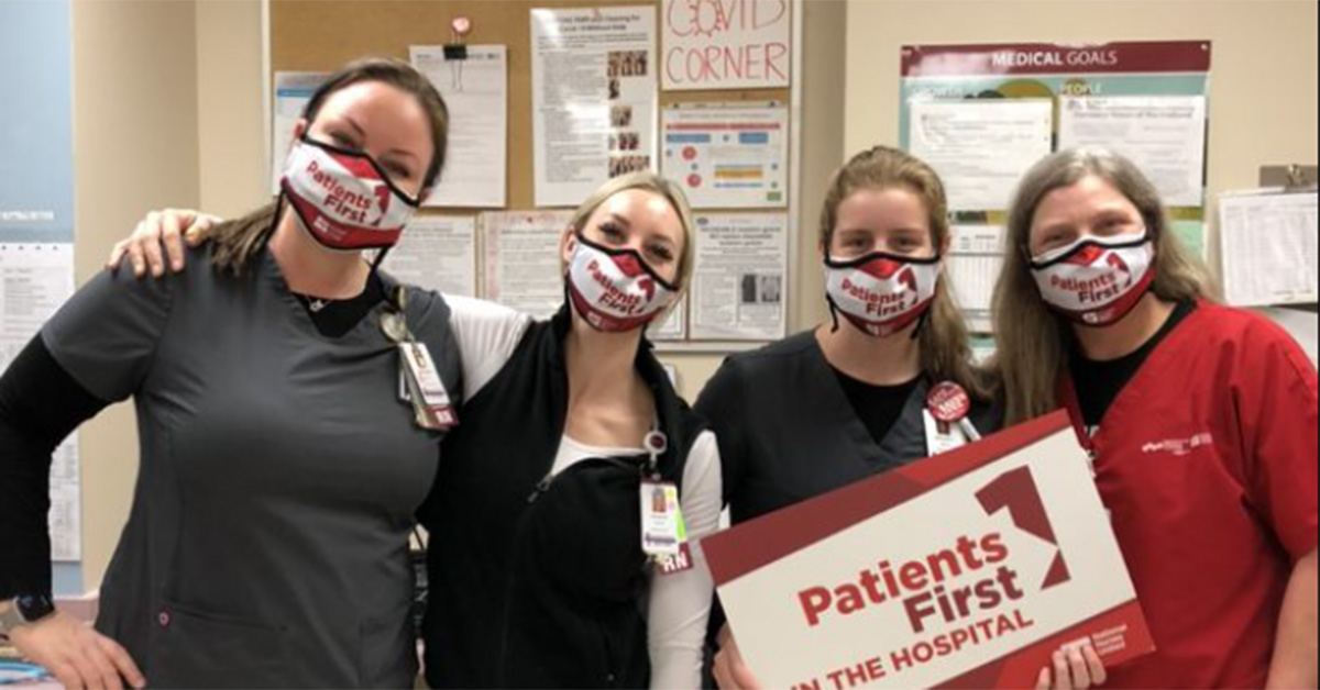 Four nurses inside hospital hold signs "Patients First"