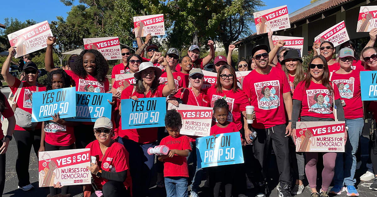 Large group of nurses and other canvassers holding signs "YES on Prop 50"