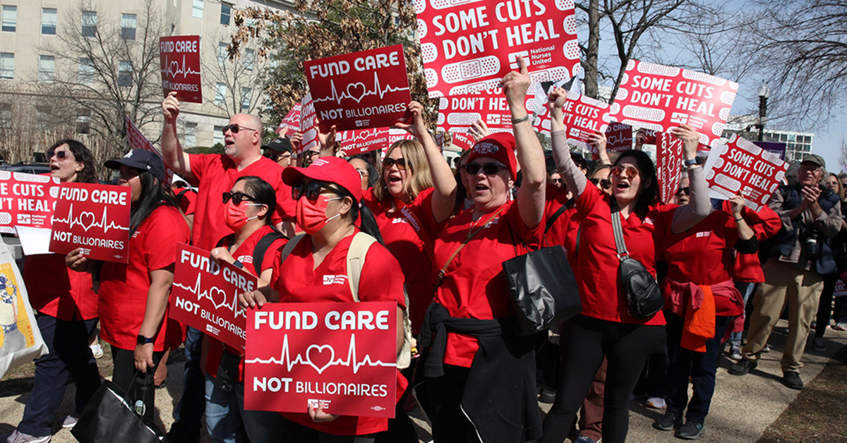 Nurses marching holding signs "Some Cuts Don't Heal" and "Fund Care Not Billionaires"