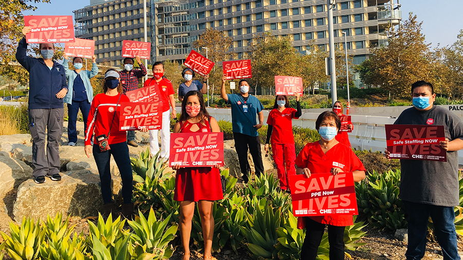 Health care workers hold signs calling fo safe staffing