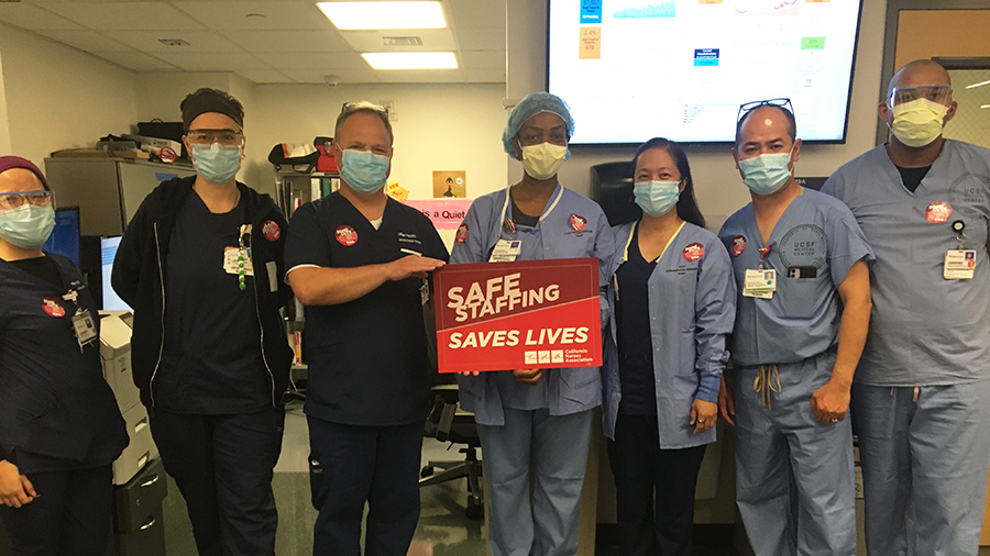 UCSF nurses hold sign "Safe Staffing Saves Lives"