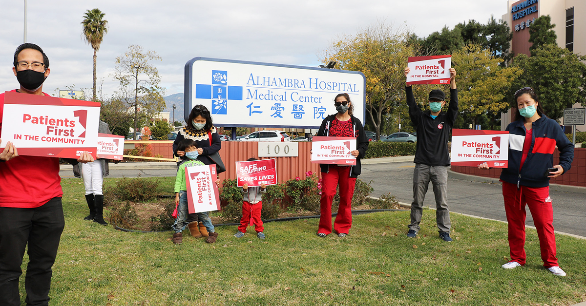 Nurses in front of Alhambra Hospital Medical Center sign hold signs calling for safe staffing and patient safety