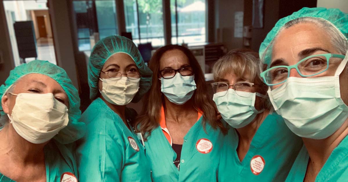 Five masked nurses inside hospital stand close together