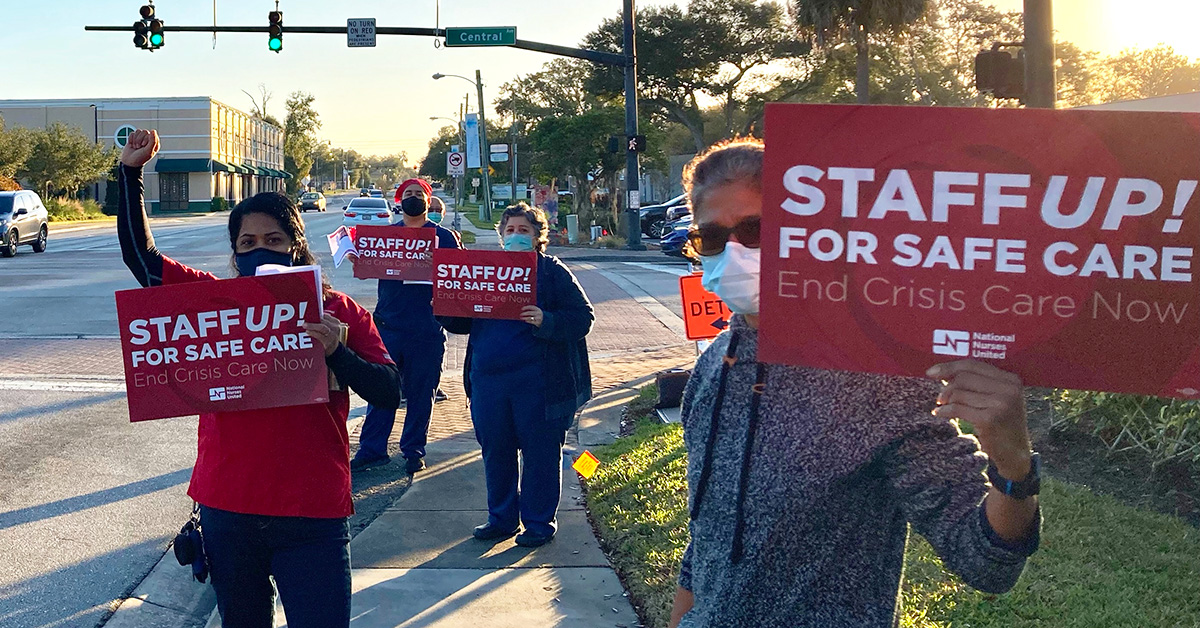 Group of four nurses outside hold signs "Staff up for safe care"