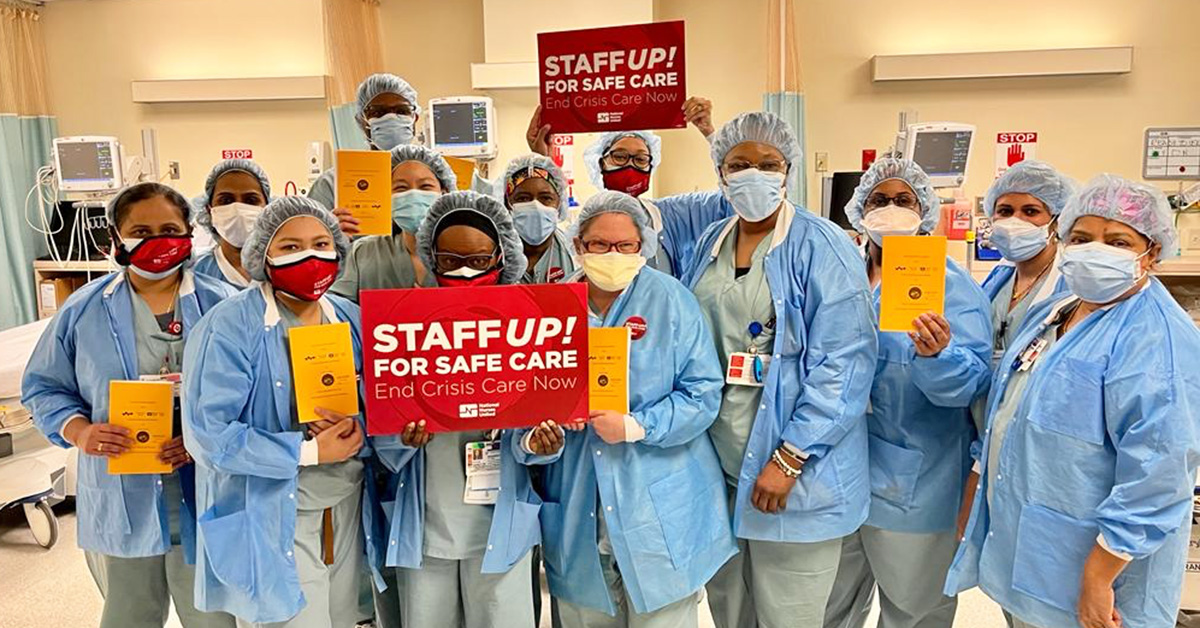 Large group of nurses inside hospital hold sign "Staff Up for Safe Care"