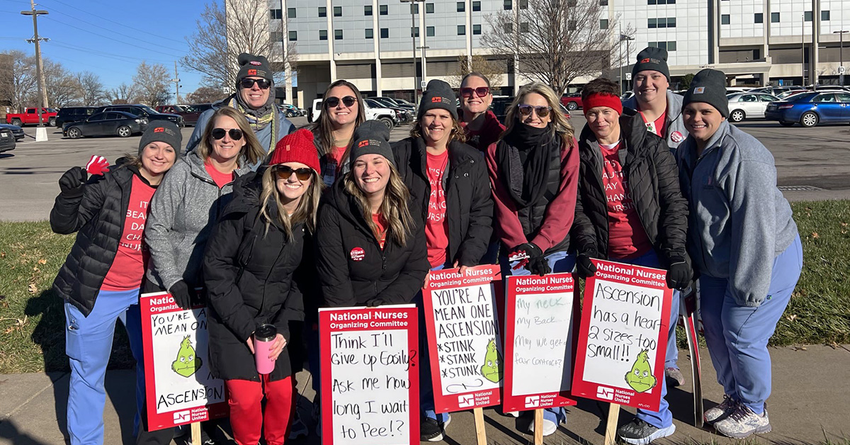 Group of nurses outside hospital holding picket signs