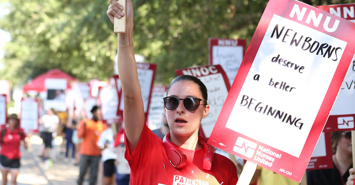 Nurse holding sign "NNU: Newborns deserve a better beginning" and shirt "Patients before profits"