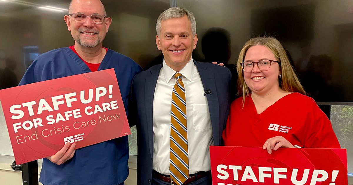 Two nurses standing with North Carolina Attorney General Josh Stein holding signs "Staff Up for Safe Patient Care"