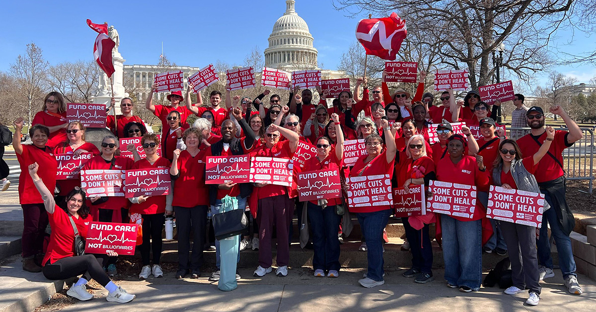 Large group of nurses outside capitol building holding signs "Some Cuts Don't Heal" and "Fund Care Not Billionaires"