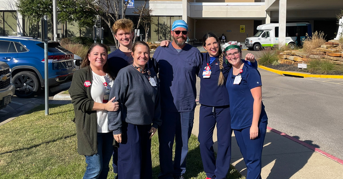 Six nurses outside hospital, smiling