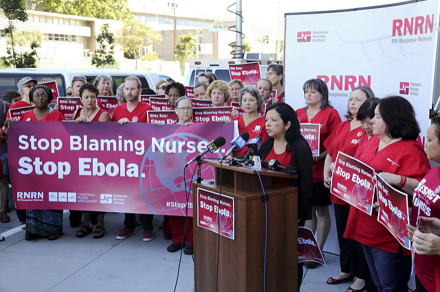 Large group of nurses holding sign "Stop Ebola Now"