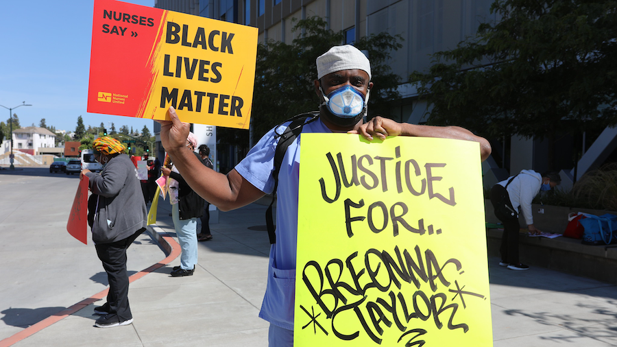 Nurse holds sign "Breonna Taylor"