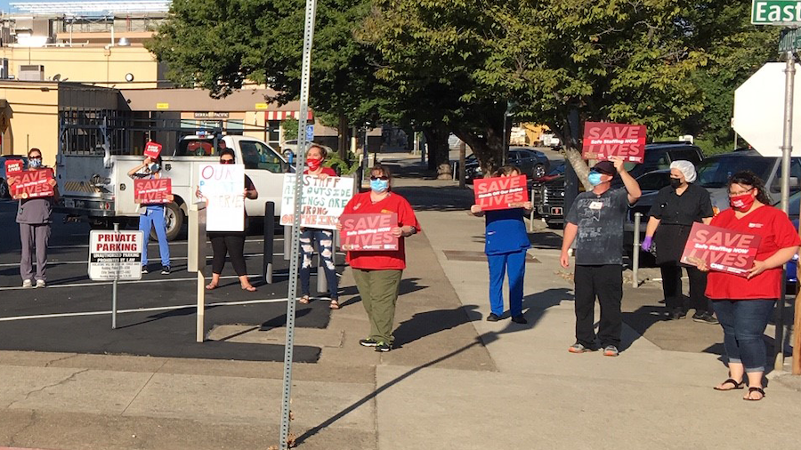 Medical workers hold signs "Safe Staffing Now"