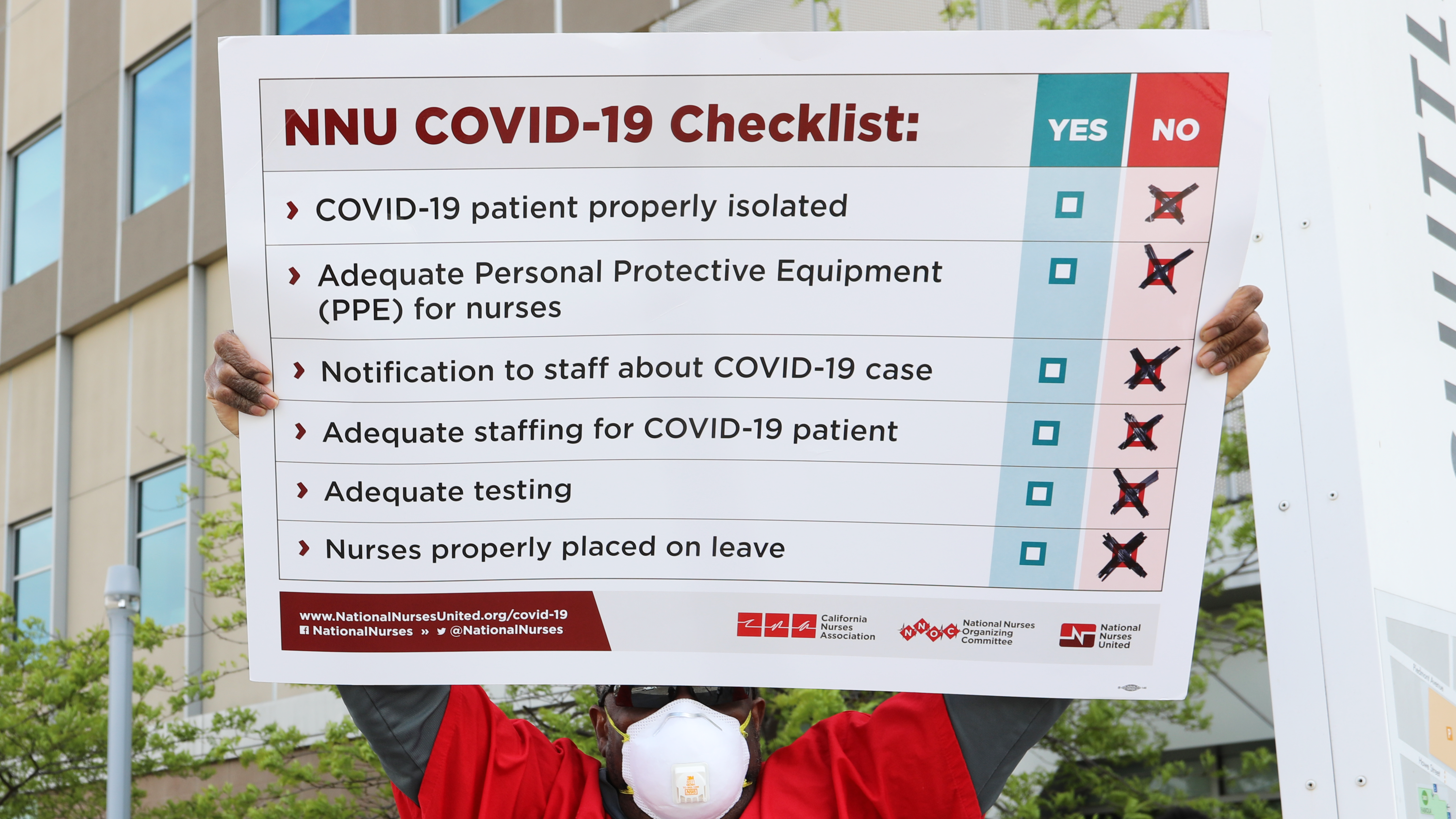 Nurse holds sign "NNU Covid-19 Checklist"