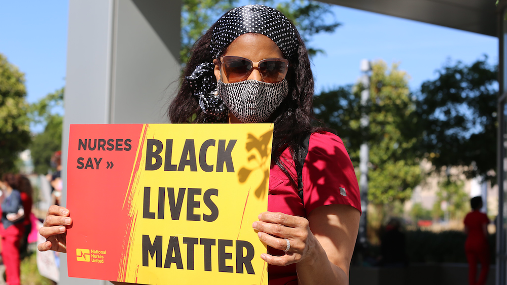 Nurse holds sign "Nurses say Black Lives Matter"