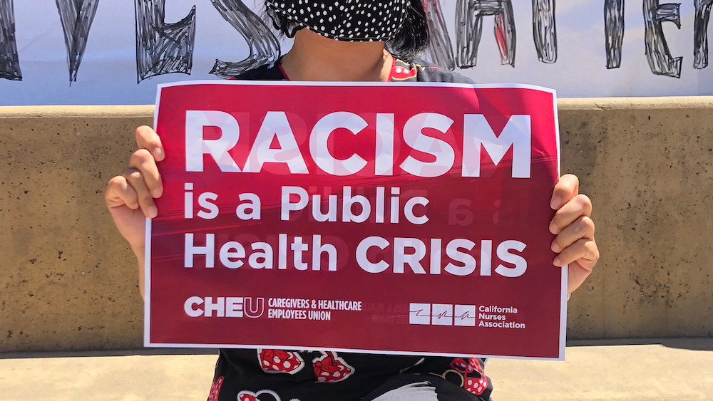 Nurse holds sign "Racism is a public health crisis"