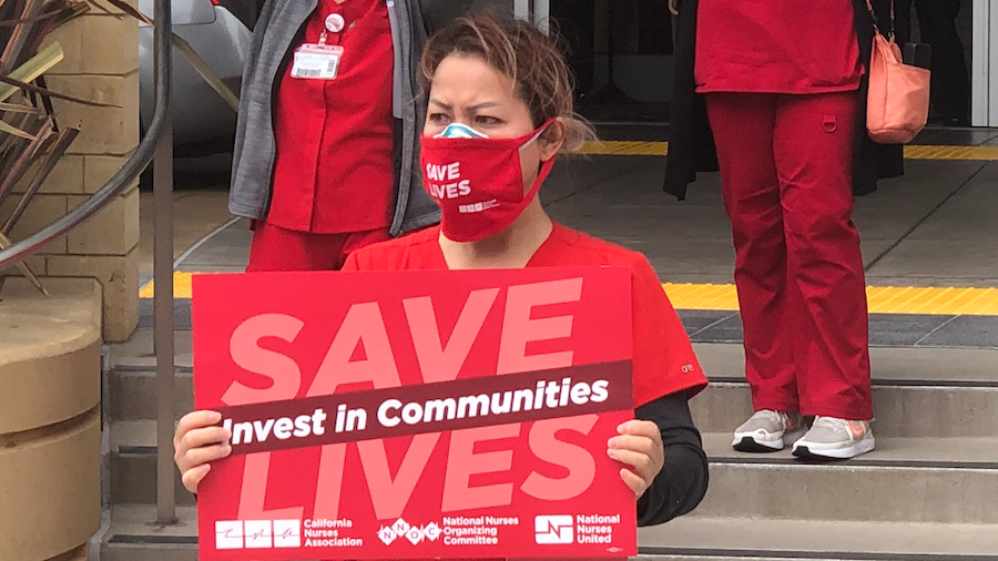 Nurse holds sign "Invest in Communities"