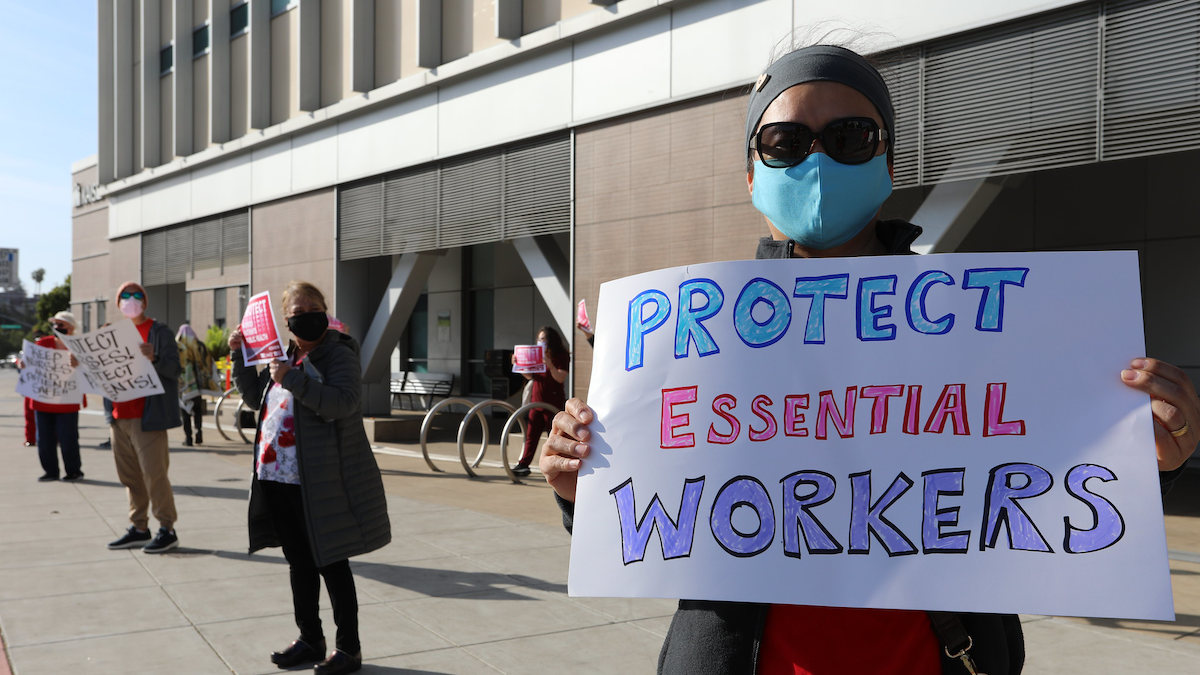 Nurse holds sign "Protect Essential Workers"