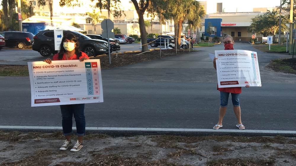 Nurses hold "COVID-19 checklist" signs outside Fawcett Memorial