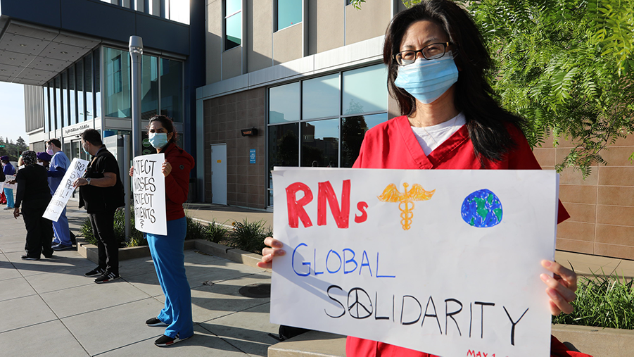 Nurse holds signs "RNs Global Solidarity"