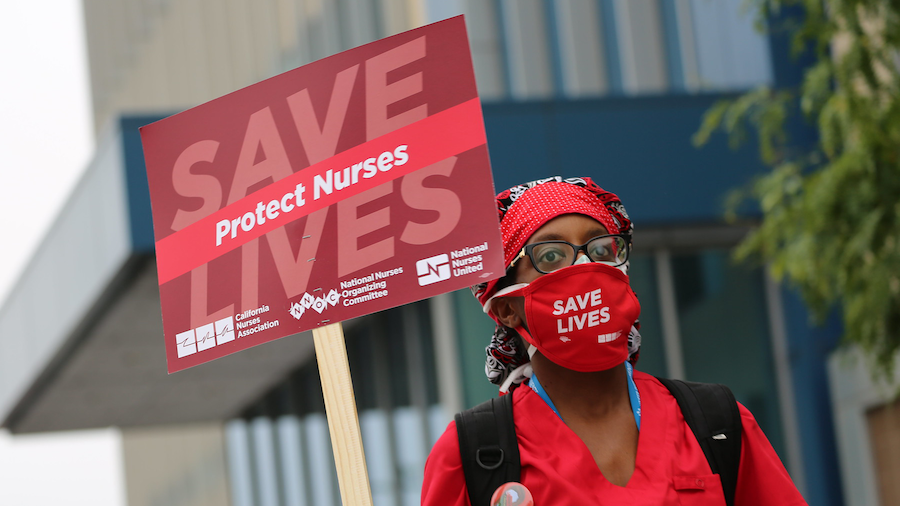 Nurse holds "Protect Nurses" sign