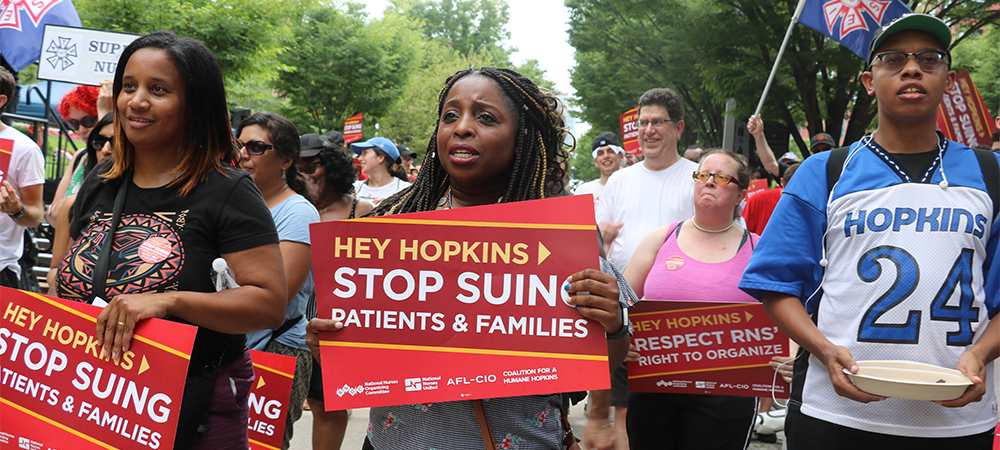 Woman holds sign "Stop suing patients and families"