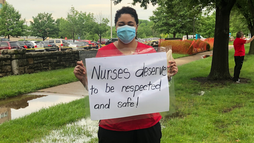Nurse holds sign "Nurses deserve to be respected and safe"