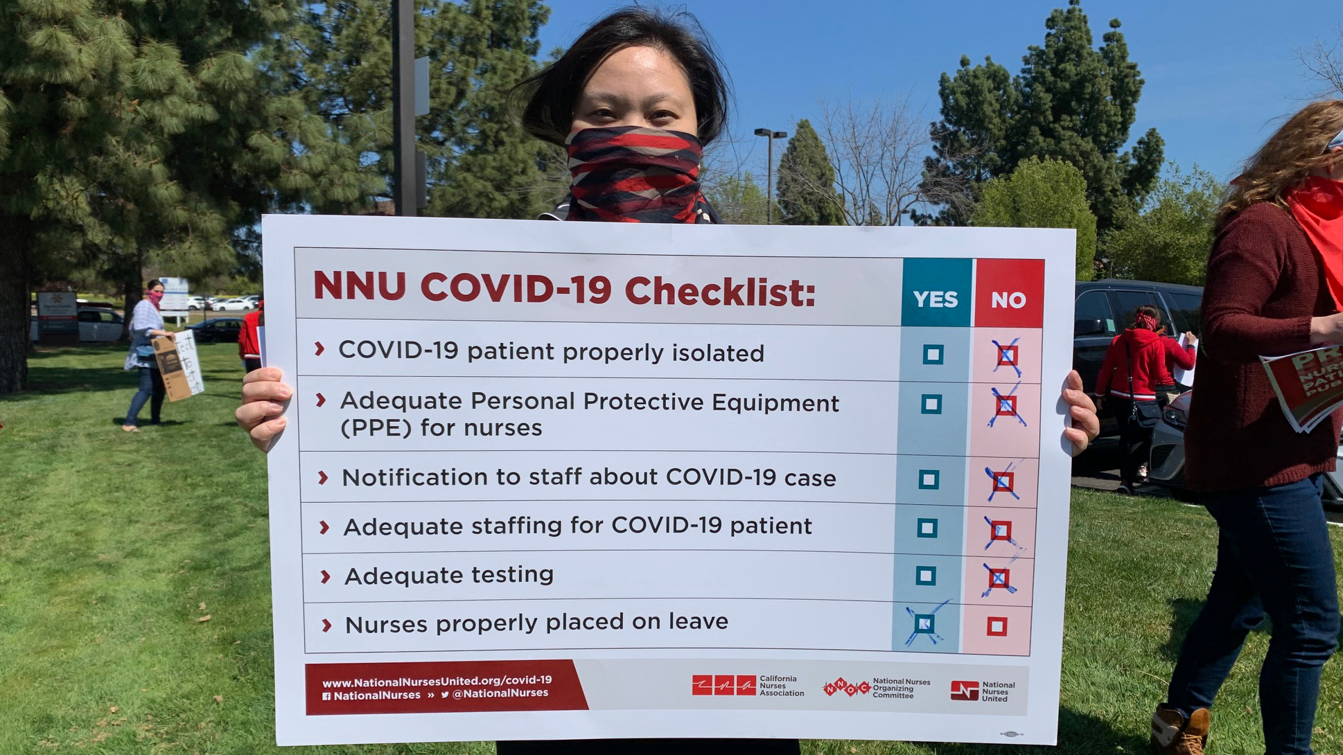 LA nurse holds sign "NNU Covid-19 Checklist"