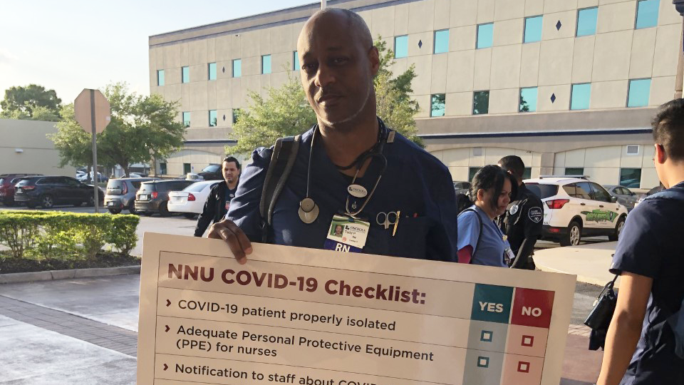 Nurse holds sign "NNU Covid-19 Checklist"