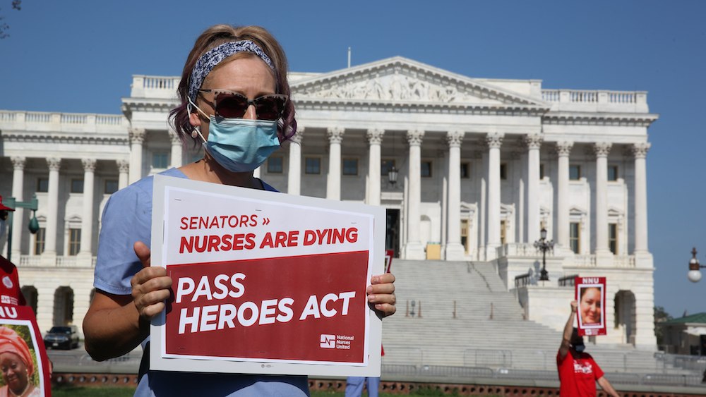 Nurse holds sign outside U.S. Senate "Pass HEROES Act"