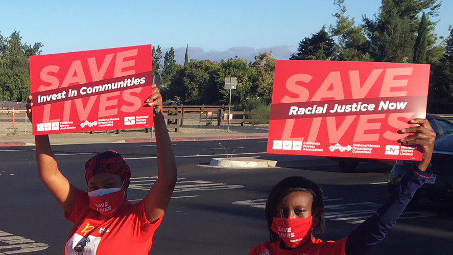 Nurse holds sign "Racial Justice Now"