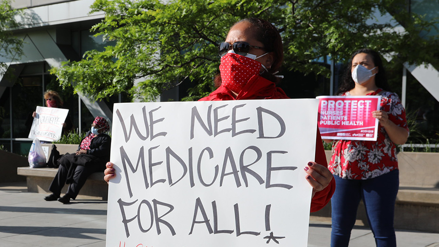 Nurse holds sign "We need Medicare for All"