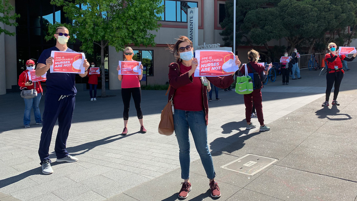 Nurses hold signs "PPE is disposable, nurses are not"