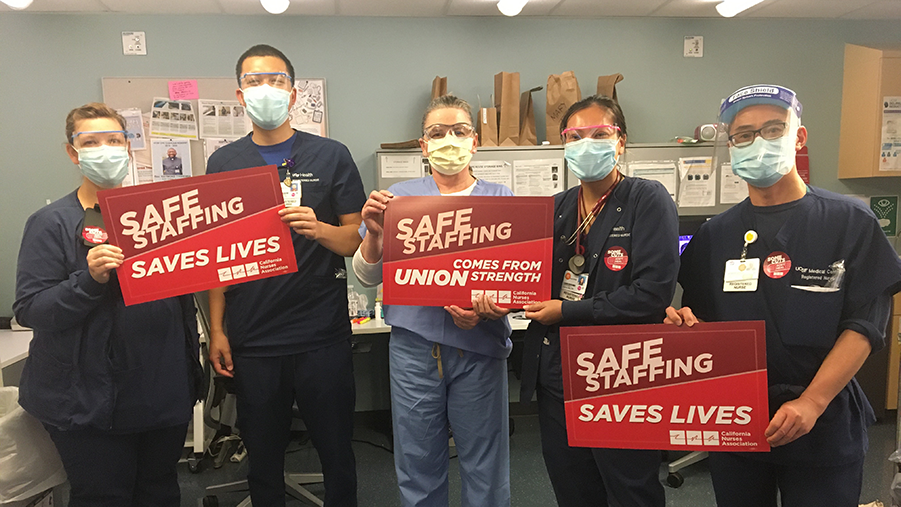 Nurses hold signs "Safe Staffing Saves Lives"