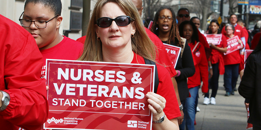 Nurse holds sign "Nurses and Veterans Stand Together"